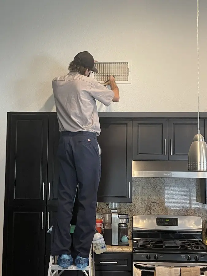 Technician inspecting an air vent during HVAC service in Bath